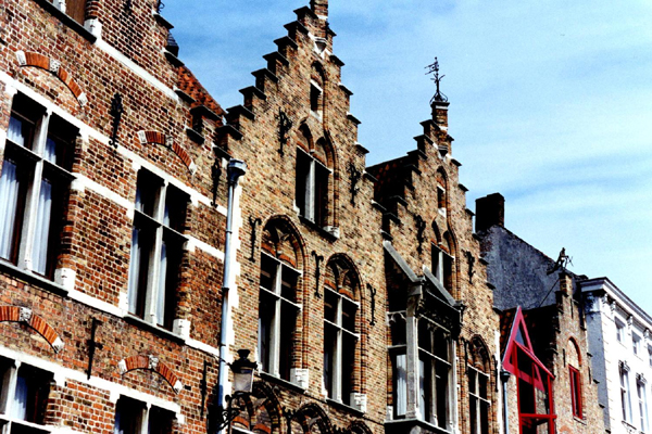Weather vanes, tall windows, and distinctive roof lines along a Brugge canal, Belgium photo